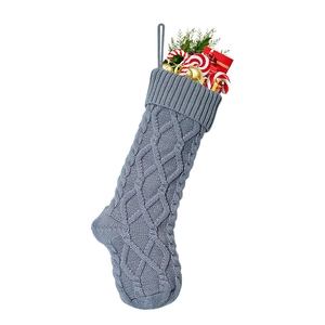 Detailed view of gray cable knit Christmas stocking filled with festive candy canes and pine