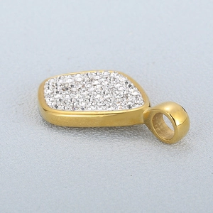 Golden rhombic pendant with shimmering pave-set zircon crystals on a grey background