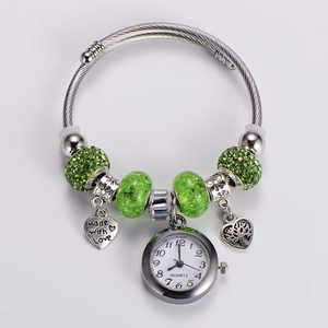 Close-up of green crystal beads and heart pendant on a stainless steel watch bracelet