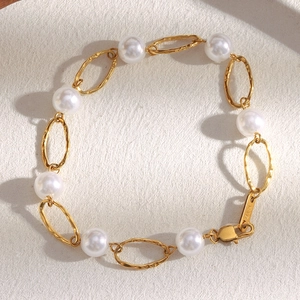 Macro shot of 18K gold plated clasp and white pearls on a minimalist chain bracelet