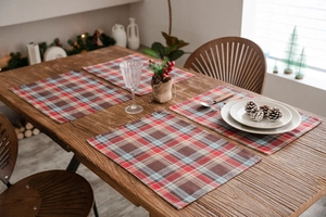 Close-up of four red and brown checkered placemats on a festive wooden dinner table