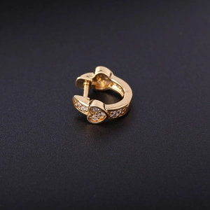 Macro shot of gold heart hoop earring with inlaid zircon crystals on a dark background