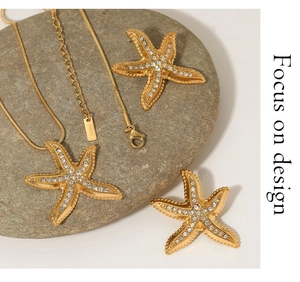Detail of gold starfish jewelry set with rhinestones and S.Steel tag on gray stone