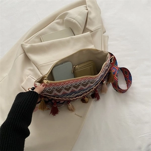 Detail view of ethnic woven crossbody bag with colorful tassels and wide strap