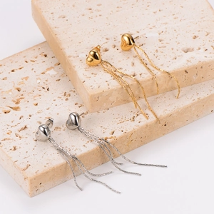 Elegant gold and silver heart tassel earrings with sleek snake chains on a stone base