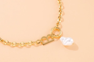 Detail of gold B letter pendant with baroque pearl on thick chain link necklace