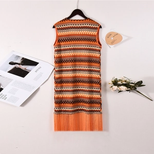 Détail du gilet en tricot bohème avec rayures orange et longues franges sur l'ourlet