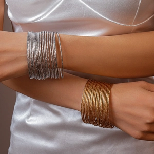 Set di 20 bracciali a cerchio metallici a strati in oro e argento sulla modella