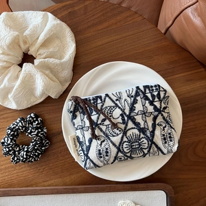Embroidered linen mini coin purse with bird pattern on a white plate and wood table