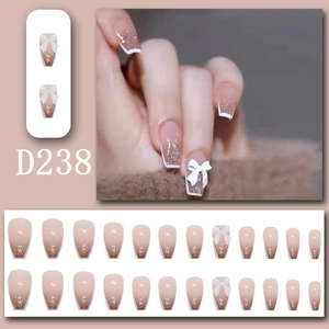 Macro detail of French gradient press-on nails with 3D bow charms and champagne glitter