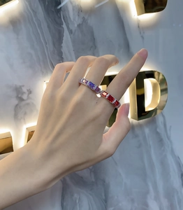 Macro shot of silver ring with colorful square-cut gemstones worn on a finger