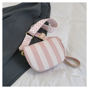 Detail of pink and white striped saddle bag with geometric wide strap and gold hardware