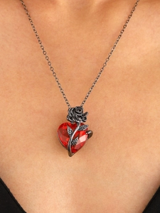 Detail of red heart crystal necklace with black rose pendant on a model's collarbone