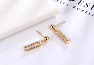Close-up of gold cylindrical drop earrings with micro-pave white zircon inlay