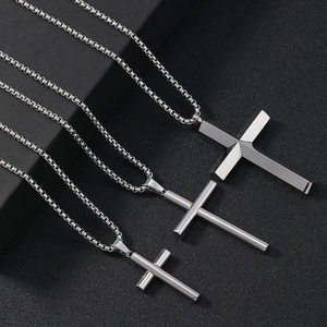 Detailed close-up of three silver cross pendants in cylinder and flat styles on box chains