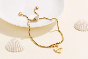 Adjustable gold heart charm bracelet with Love engraving and slide buckle closure
