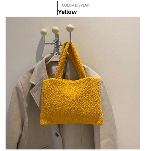 Detail of yellow fuzzy plush tote bag showing soft faux lamb wool texture on beige coat