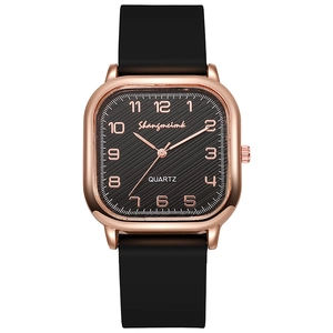Detail of square rose gold watch case with textured black dial and Arabic numerals