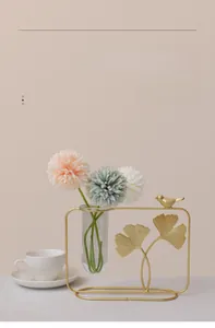 Detail of golden ginkgo leaf iron vase with glass tube and bird ornament on desk