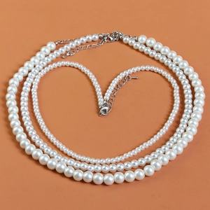 Detailed close-up of triple-layered pearl necklace with adjustable silver metal clasp