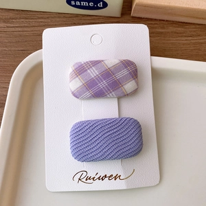 Detail of two-piece purple plaid and wavy textured fabric square hair clips on display card