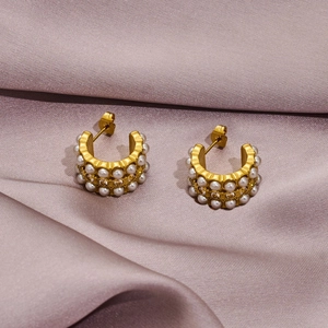 Macro shot of gold-plated hoop earrings with pearls and crystals on purple silk