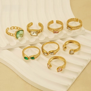 Detail of adjustable gold rings with emerald and pink zircon set on a wavy white stand