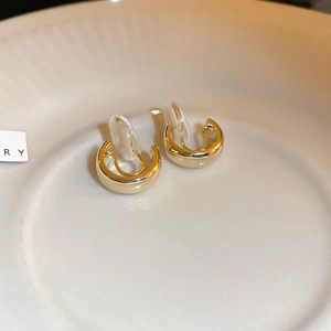 Macro shot of gold-plated C-shaped bow earrings with soft silicone pads for non-pierced ears