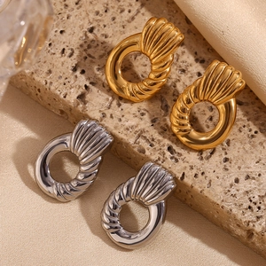 Detail of twisted texture gold and silver petal earrings on silk and stone background