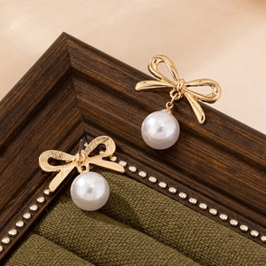Elegant gold bow earrings with white pearl pendants in a luxury green velvet jewelry box