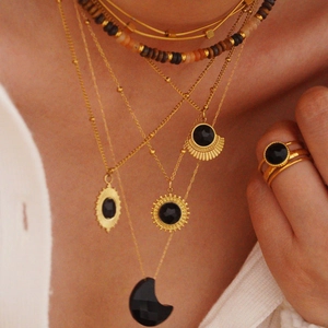 Close-up of layered 14K gold plated necklaces with black agate crescent pendants
