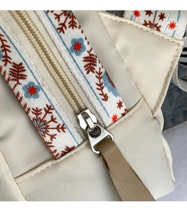 Detail of bohemian jacquard strap and silver hardware on cream nylon shell bag