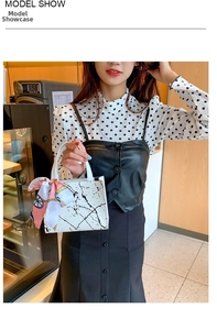 Lifestyle view of white marble pattern handbag with decorative pink silk scarf accent