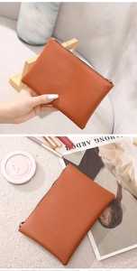 Brown lychee grain PU leather makeup pouch held by hand with fashion accessories