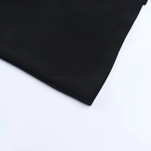 Gros plan des coutures fines et de la texture tissée sur l'ourlet de cette robe noire
