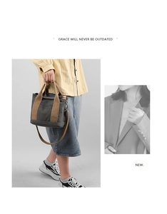 Detail view of a thick dark gray canvas tote bag featuring brown woven straps and metal hooks