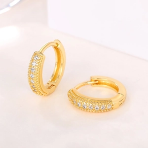 Detail of gold hoop earrings with sparkling inset crystals and textured metallic finish