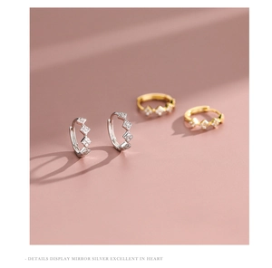 Detail view of gold and silver geometric diamond-encrusted earrings with square zircons