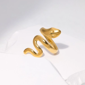 Detail view of golden snake-shaped adjustable ring on a white textured stone surface