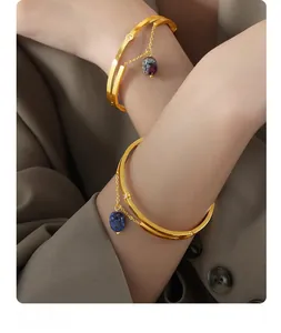 Detail of gold titanium steel bangle featuring hanging natural gemstone charms on the wrist