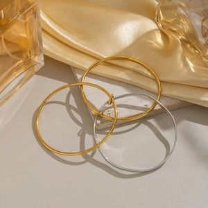 Close-up of minimalist gold and silver bangles on elegant silk fabric background