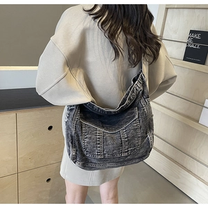 Détail d'un sac bandoulière en denim vintage avec surpiqûres et grande poche frontale