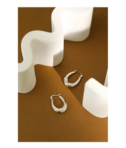 Minimalist polished S925 sterling silver oval hoop earrings on a textured brown background