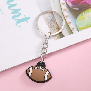 Detail view of brown PVC American football keychain with metal ring on pink background