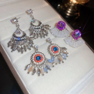 Detailed macro view of three pairs of ethnic-style crystal earrings in a velvet tray