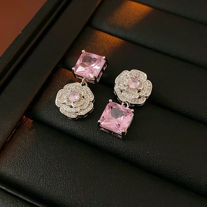 Detail of vintage silver earrings with pink gemstones and zircon flowers on black tray