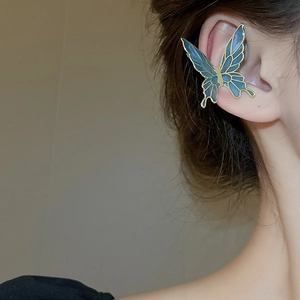 Detailed view of a blue butterfly ear cuff with golden trim on a model's ear