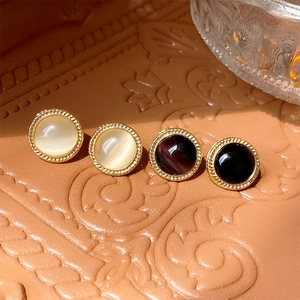 Detailed shot of vintage round cat eye stone stud earrings with gold twisted edge frames