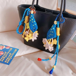 Close-up of hand-crocheted blue star charms and yellow smiley face beads on a black leather bag