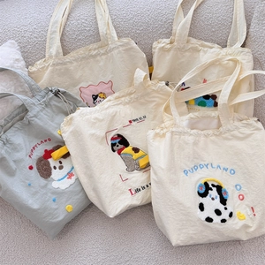 Flat lay of multiple canvas drawstring handbags with puppy embroidery and various patterns